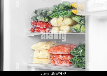 Sacchetti di plastica con diverse verdure congelate in frigorifero Foto Stock