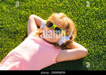 Il bambino si diverti con la sua musica preferita. Bambino con cuffie che ascolta musica all'aperto Foto Stock