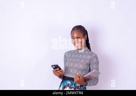 Allegro studente femminile con smartphone e libri degli esercizi in piedi Foto Stock