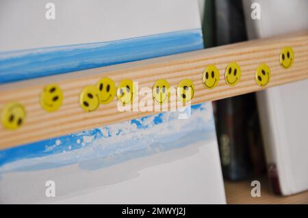 Adesivi facciali sorridenti su una libreria di legno, camera per bambini, adesivi felici Foto Stock