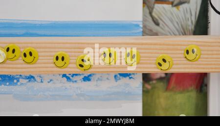 Adesivi facciali sorridenti su una libreria di legno, camera per bambini, adesivi felici Foto Stock