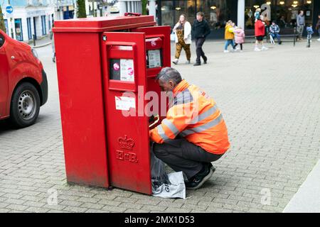 Royal mail lavoratore postale svuotamento casella postale rossa di lettere e posta nella città di Carmarthen gennaio 2023 KATHY DEWITT Foto Stock