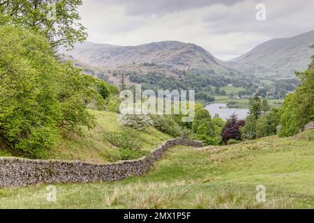 English Lake District, Cumbria, UK - Vista verso il lago Grasmere sul sentiero tra Elterwater e Grasmere con pareti in pietra che conducono in discesa Foto Stock