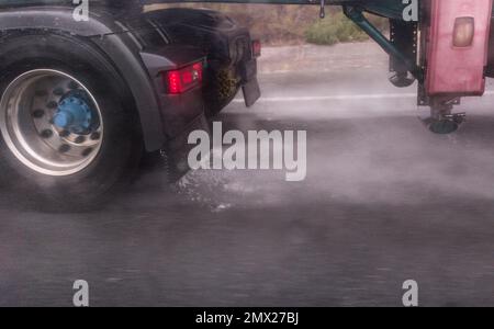 Le ruote dei camion spruzzano acqua sulla strada. Concetto di guida in caso di maltempo Foto Stock