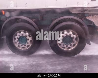 Le ruote dei camion spruzzano acqua sulla strada. Concetto di guida in caso di maltempo Foto Stock