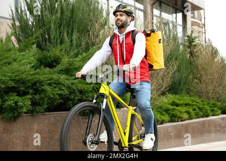 Corriere con borsa termica in bicicletta all'aperto. Servizio di consegna cibo Foto Stock