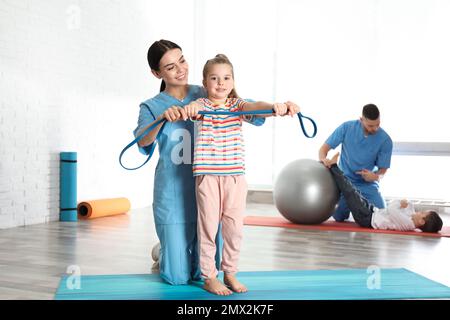 Ortopedici che lavorano con bambini piccoli in palestra ospedaliera Foto Stock