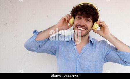 Uomo italiano che balla ridendo mentre ascolta musica con le cuffie. Uomo divertente Foto Stock