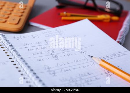 Notebook con compiti a casa e matita su tavolo grigio, primo piano Foto Stock