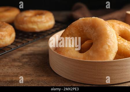 Deliziose ciambelle in scatola su tavolo di legno, primo piano Foto Stock