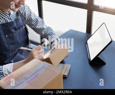 Avvio di piccole imprese PMI proprietari imprenditrici controllare gli ordini online per prepararsi a imballare le scatole, vendere ai clienti, PMI idee di business Foto Stock