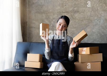 Giovane imprenditore asiatico donna con molte scatole di pacchi e felice lavoro di vendita online, ottenere un ordine dai clienti, e prendere accordi per la consegna da Foto Stock