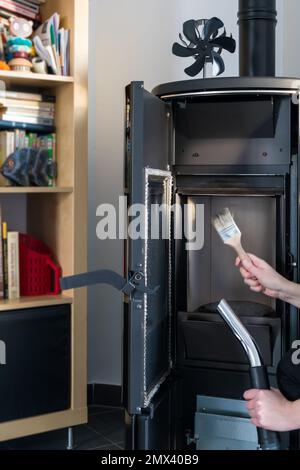 Donna pulizia stufa a pellet con accessori come aspirapolvere o spazzola Foto Stock