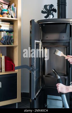 Donna pulizia stufa a pellet con accessori come aspirapolvere o spazzola Foto Stock