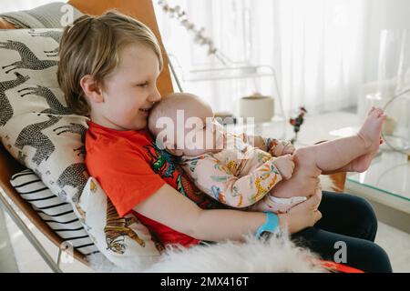 Ragazzo seduto con bambino fratello Foto Stock