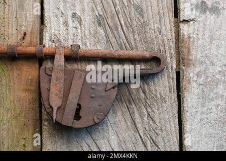 Un vecchio lucchetto e bullone su una porta di un cottage, Sicilia. Probabilmente fatto nel villaggio da un artigiano locale Foto Stock