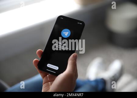MYKOLAIV, UCRAINA - 16 MARZO 2020: Uomo in mano iPhone 11 con app telegramma sullo schermo in interni, primo piano Foto Stock