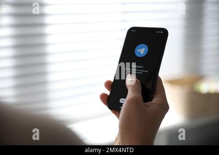 MYKOLAIV, UCRAINA - 16 MARZO 2020: Uomo in mano iPhone 11 con app telegramma sullo schermo in interni, primo piano Foto Stock