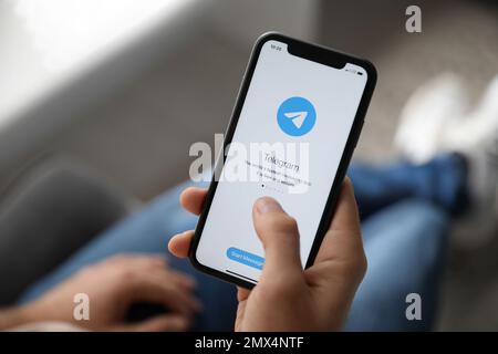 MYKOLAIV, UCRAINA - 16 MARZO 2020: Uomo in mano iPhone 11 con app telegramma sullo schermo in interni, primo piano Foto Stock