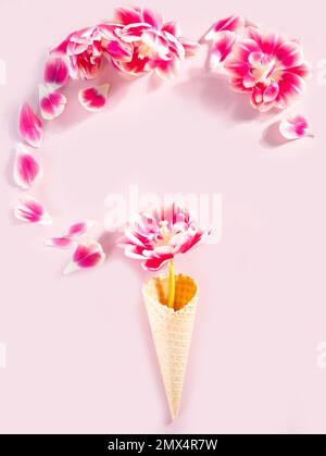 Cono gelato con fiori rosa e petali. San Valentino concetto. Giacitura piatta Foto Stock
