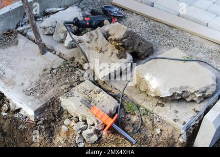 Sfocare le pietre di pavimentazione sfondo pavimentazione. Installazione degli strumenti in primo piano. Molti grossi blocchi di pietra e lastre su pietra frantumata. Fuori fuoco Foto Stock