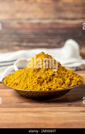 Polvere di Masala al curry. Polvere di curcuma o polvere di curry spezia in una ciotola su fondo di legno. İndian spezie. Concetto di spezie secche. primo piano Foto Stock