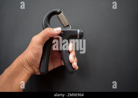 Esercizio a mano, schiacciamento di un'impugnatura, presa di una pinza per esercizi a mano da parte di un uomo. Foto Stock