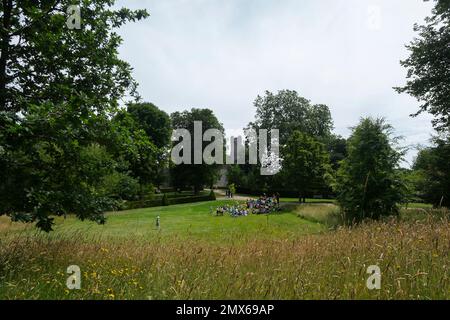 Un gruppo di bambini in una gita scolastica seduti sull'erba nei giardini di Arundel Castle, West Sussex, UK Foto Stock