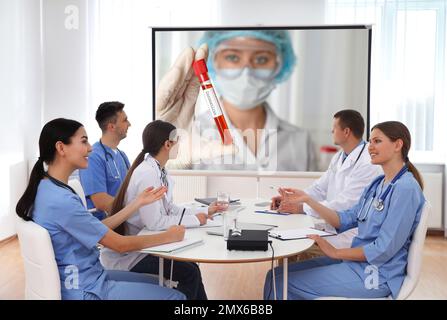 Team di medici che utilizzano il videoproiettore durante la conferenza coronavirus in ufficio Foto Stock