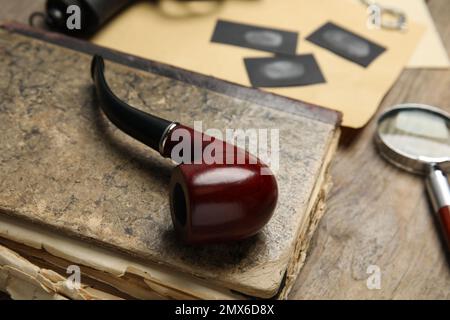 Tubo di tabacco e vecchio libro su tavola di legno, primo piano. Luogo di lavoro del detective Foto Stock