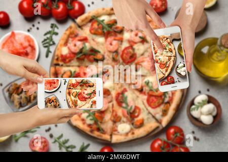 Cibo blogger scattare foto di deliziosa pizza di pesce al tavolo grigio chiaro, primo piano Foto Stock