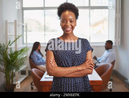 Ritratto di una donna sorridente di affari nera in piedi con i dipendenti in ufficio Foto Stock