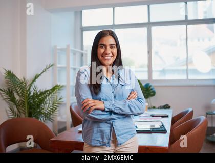 Giovane donna indiana si alza in braccia da ufficio ripiegate, moderne piante da sala riunioni Foto Stock