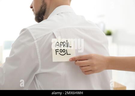 Donna che si attacca APRILE PAZZO nota al collega di nuovo in ufficio, primo piano Foto Stock