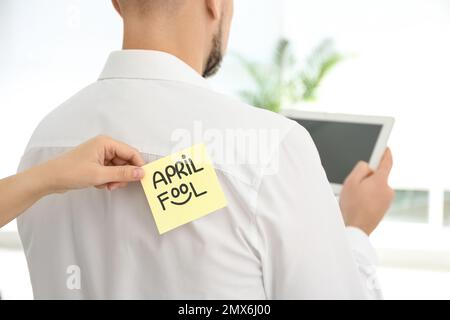 Donna che si attacca APRILE PAZZO nota al collega di nuovo in ufficio, primo piano Foto Stock