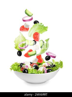 Ingredienti freschi per insalata greca che cade in ciotola su sfondo bianco Foto Stock