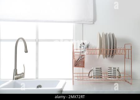 Pulire i piatti sulla griglia di asciugatura all'interno della cucina  moderna Foto stock - Alamy