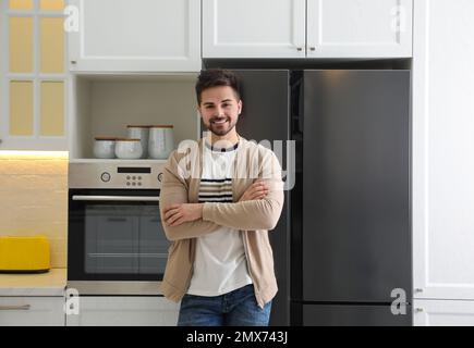 Felice giovane uomo vicino al frigorifero in cucina Foto Stock