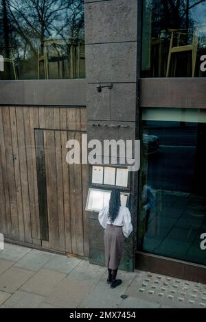 Una cameriera inserisce un nuovo menu al di fuori di un business su Piccadilly, il 2nd gennaio 2023, a Londra, Inghilterra. Foto Stock