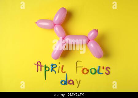 Animale palloncino e frase FOOL's DAY APRILE su sfondo giallo, piatto giacitura Foto Stock