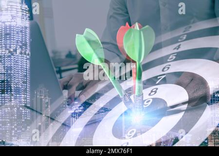 Uomo d'affari che lavora con computer portatile e dart board. Doppia esposizione Foto Stock