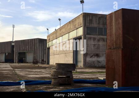 Complesso industriale abbandonato chiuso da un cancello nella campagna italiana Foto Stock