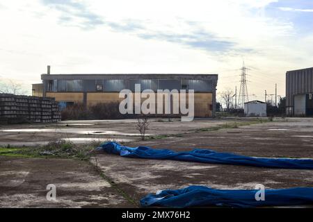 Complesso industriale abbandonato chiuso da un cancello nella campagna italiana Foto Stock