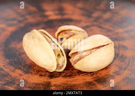 Tre pistacchi senza guscio in un piatto di argilla, primo piano. Foto Stock