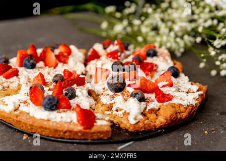 La Fregolotta, una tradizionale torta o torta di briciole italiana, è vista dall'alto su un tavolo, coperto di mascarpone, mirtilli rossi e lamponi. Traditio Foto Stock