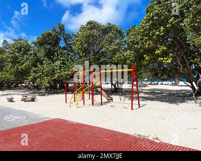 Un piccolo playset per bambini, con altalene e uno scivolo, sulla spiaggia, Eagle Beach, Aruba. Foto Stock