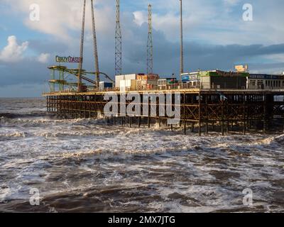 Blackpool molo sud in una giornata tempestosa con il vento che urla e le onde del mare irlandese con tutte le giostre divertenti fiera chiuso per l'inverno selvaggio Foto Stock