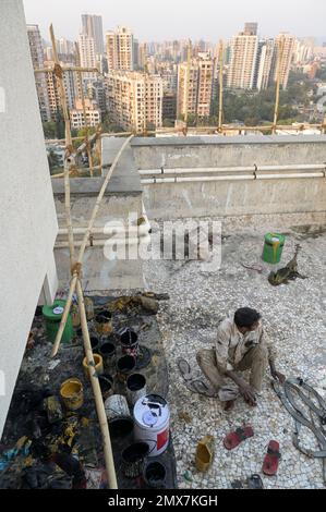 INDIA, Mumbai, torre di appartamenti in fase di ristrutturazione, impalcatura di bambù, lavoratore migrante da UP e Bihar facendo lavori di verniciatura, durante il periodo di lavoro stanno vivendo sul tetto / INDIEN, Mumbai, Wohnhaus mit Baugerüst aus Bambus, Wanderarbeiter aus UP und Bihar bei Malerarbeiten, während der Arbeitsphase wohnen sie auf dem Dach Foto Stock