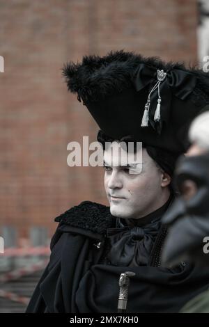 Carnevale di Venezia. Un uomo con un volto coperto da uno strato di polvere bianca nello stile di un'aristocrazia medievale in costume nero carnevale - cappello alto Foto Stock