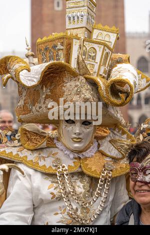 Carnevale di Venezia. Un uomo in costume da carnevale di un re con un  bastone e un enorme cappello d'arte con case veneziane su di esso si posa  per strada a Venezia Foto stock - Alamy